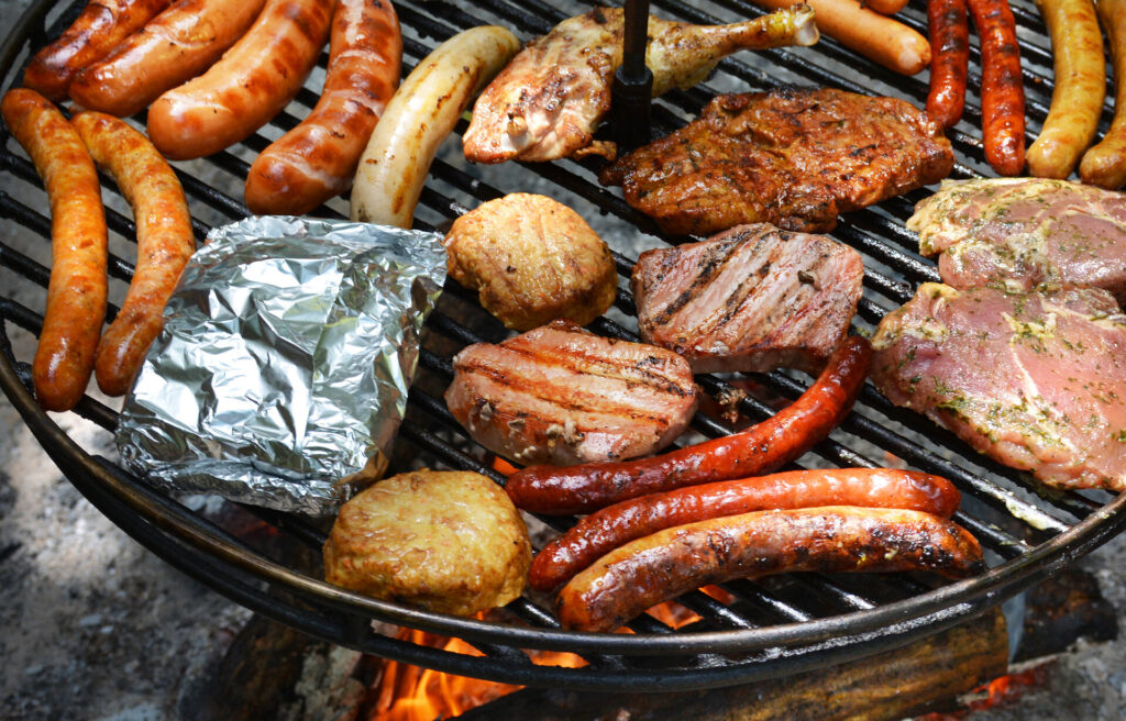 Schwenkgrill mit verschiedenen Fleischwaren belegt