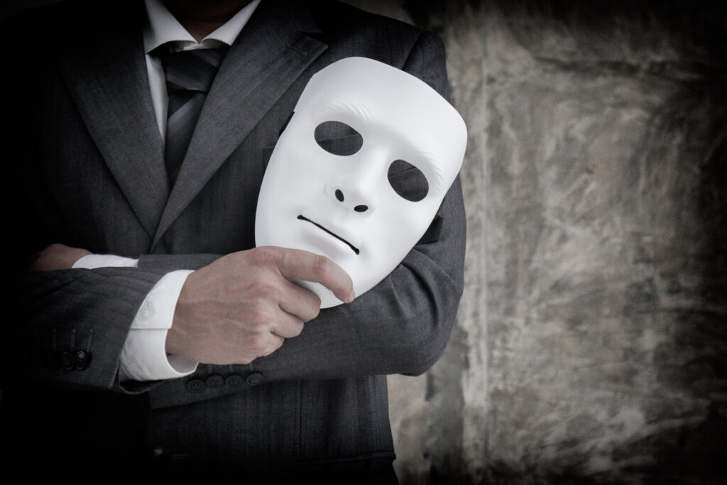 Geschäftsmann hält weiße Maske in seiner Hand, als Zeichen für Betrug, Fälschen und Verrat.