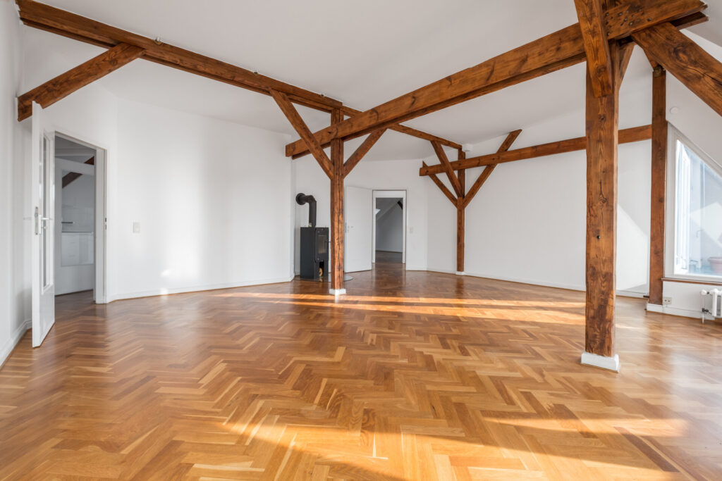 Leeres Loftzimmer mit Kamin, Holzbalken und Parkettboden