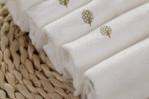 Weiße, gefaltete Handtücher aus Baumwollstoff mit Logodesign.