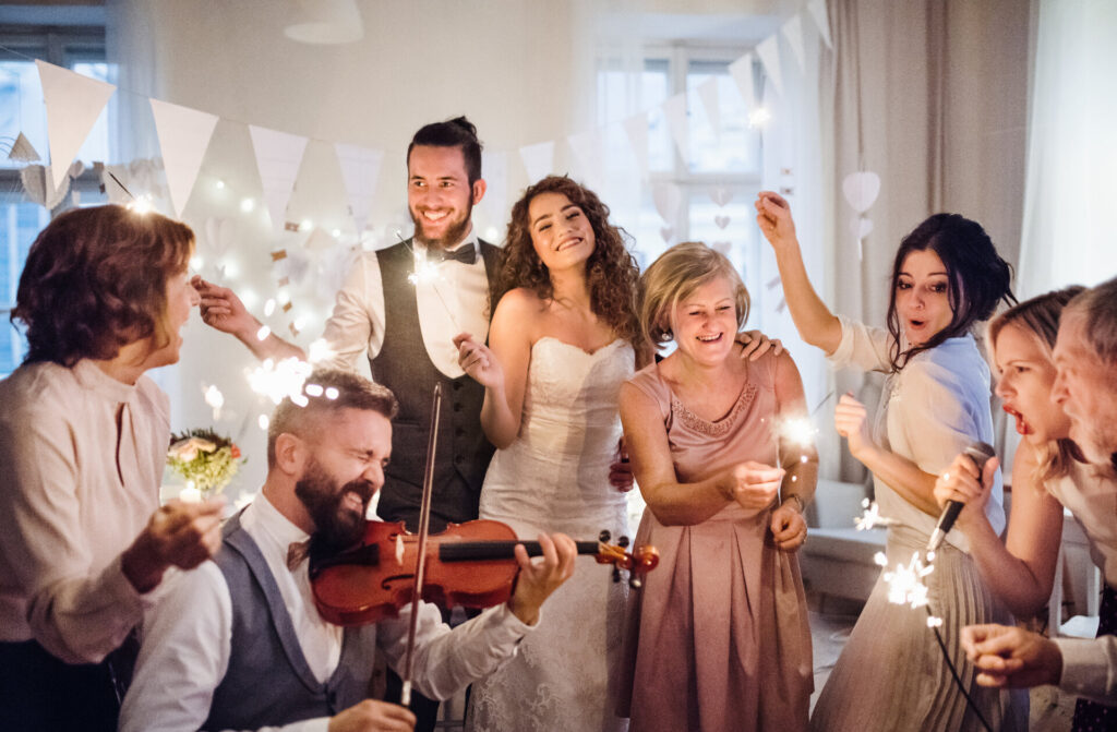 Eine junge Braut, ein Bräutigam und andere Gäste tanzen und singen auf einer Hochzeitsfeier.